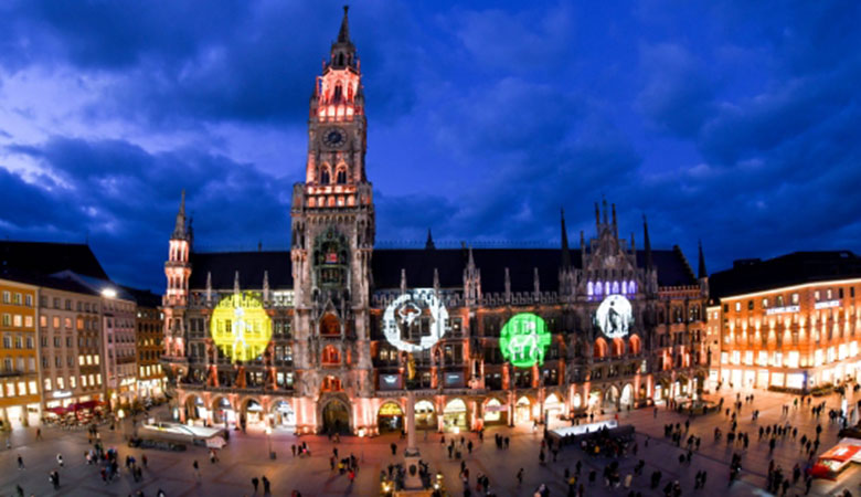 Das Münchner Rathaus bei Nacht. Auf die Fassade sind Symbole für verschiedene Formen von Behinderung projiziert.